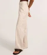 Pantalón wide leg de cintura alta con rayas verticales, bolsillos y cinturón fino de tela.