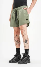 Short de baño verde militar de calce regular, con elástico en la cintura, cordón de ajuste con inscripción "LUXURY" y tres bolsillos.