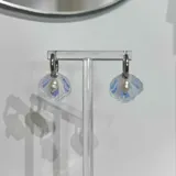 Aros colgantes con argolla de acero quirúrgico hipoalergénico y dije de concha marina con una perla de río natural.