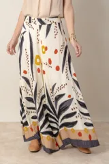 Pantalón palazzo de viscosa color crudo con estampado de hojas y flores en tonos azules y marrones. Cintura elastizada en la parte trasera.