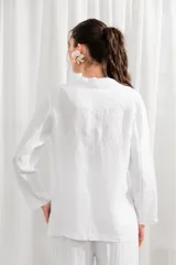 Blazer de lino blanco con estampado floral en tonos rosa y verde, corte holgado, cuello solapa y bolsillos laterales.