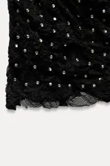 Falda midi negra de encaje con strass, tiro medio y cintura elástica.