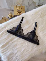 Bralette negro de encaje con diseño triangular, breteles regulables y cierre trasero con gancho.