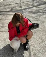 Campera roja de cuero sintético, con cuello solapa, cierre cruzado con botones a presión y cinturón con hebilla.