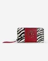 Billetera de cuero con estampado animal print de cebra en los extremos y panel central rojo con apliques metálicos. Incluye cierre y tira de cuero roja en el cierre.