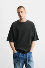 Camiseta negra de corte relaxed fit, cuello redondo y mangas cortas. Tejido de punto con textura acanalada y efecto lavado.