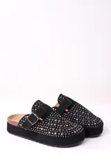 Zueco negro con plataforma, tachas plateadas y hebilla ajustable.