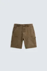 Bermuda color verde militar, de corte relaxed fit, con bolsillos frontales y traseros tipo plaqué, detalle de tira y bolsillo multifunción en la pierna, y bajo irregular.