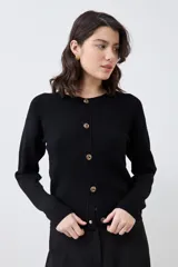 Chaqueta tejida negra con botones dorados, de corte clásico y mangas largas.