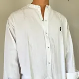 Camisa blanca de lino con cuello mao, manga larga y corte regular. Presenta un pequeño bordado en el pecho.