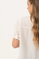 Blusa blanca de mangas cortas con cuello redondo y abotonadura frontal.