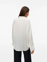 Camisa blanca traslúcida con textura de líneas verticales, cuello clásico, cierre frontal con botones, mangas largas con puños abotonados y corte holgado.