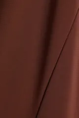 Vestido tobillero marrón sin mangas en punto tupido, con escote en V, sección drapeada con nudo decorativo y detalles cut-out adelante, y falda con leve vuelo.
