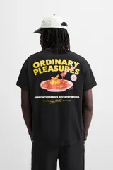 Camiseta negra de corte relaxed fit, cuello redondo y manga corta. Estampado combinado en el frente con la frase "Comfort Food!!! Our Daily Specials" y un dibujo de una flor.