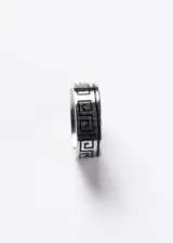 Anillo de acero quirúrgico plateado con diseño labrado de guarda griega en color negro.