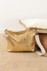 Cartera dorada con textura de piel de serpiente, cierre superior con cremallera y correa de hombro ancha desmontable en color beige.
