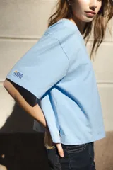 Remera blanca de algodón con cuello redondo y mangas cortas. Presenta un bordado del sol de la bandera uruguaya en el pecho.