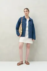 Vestido corto blanco de algodón con bordado floral en relieve, escote redondo con abotonadura frontal y mangas amplias.