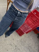 Pantalón jean azul oscuro, de corte wide leg y tiro medio. Presenta detalles de costuras diagonales en la parte superior.