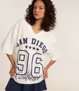 Remera blanca de algodón con cuello en V y corte amplio. Estampado frontal con la inscripción "San Diego", el número 96 y cinco estrellas. Estilo deportivo americano.
