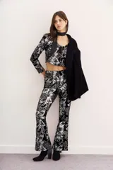 Blazer negro de terciopelo con estampado floral plateado, corte cropped y mangas largas.