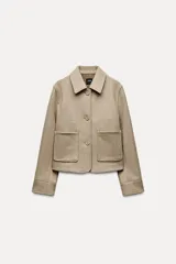 Chaqueta corta negra de cuello solapa y manga larga con puños. Tiene bolsillos de parche en el frente y cierre frontal con botones.