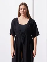 Kaftan blanco largo con mangas cortas y abertura central. Presenta apliques de puntilla en el escote, cintura y ruedo. Se ata en la cintura con un lazo.