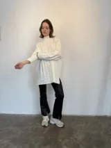Sweater tejido en lana italiana con alpaca y viscosa, color crudo, con cuello alto y mangas largas. Diseño con trenzas en el frente y mangas. Corte holgado.