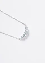 Collar de plata 925 con cinco piedras de topacio celeste engarzadas en forma de arco, con engaste tipo bisel. La cadena es de eslabones finos.