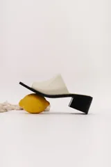 Sandalia marrón de cuero con punta cuadrada, talón abierto y faja ancha. Tiene detalle de elástico oculto en la cara interna de la capellada. El forro y la plantilla son de cuero vacuno.