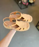 Sandalias de cuero color beige con tiras entrecruzadas y hebilla lateral.