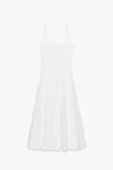 Vestido midi blanco de popelín con escote corazón y volantes. Tiene tirantes finos con detalle de lazo, forro interior combinado y cierre lateral con cremallera oculta.
