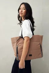 Bolso tote negro de nylon con diseño acolchado, asas largas para llevar al hombro, cierres metálicos laterales y detalle de cordón.