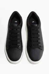 Zapatillas negras de cuero sintético con cordones negros y suela gruesa blanca.