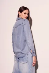 Camisa de denim de corte al cuerpo, con dos bolsillos frontales y cierre de botones.