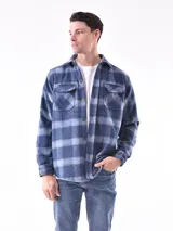 Sobrecamisa a cuadros azul y gris con cuello clásico, cierre frontal con botones, dos bolsillos con solapa abotonada en el pecho y puños abotonados.