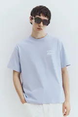 Remera celeste de algodón con cuello redondo y estampado frontal con la palabra "VIGNAUD" y un dibujo de una lancha.