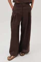 Conjunto de dos piezas color marrón oscuro, compuesto por un top sin mangas de corte recto y un pantalón de lino de tiro alto, pierna ancha y pinzas frontales.