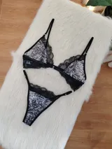 Conjunto de lencería compuesto por un corpiño triangular sin aro con estampado animal print y detalles de encaje negro, y una bombacha tipo colaless con el mismo estampado y borde de encaje negro. El corpiño tiene cierre frontal.