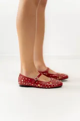 Chatas negras de cuero con correa sobre el empeine y hebilla plateada. Decoradas con tachas plateadas y doradas de diferentes tamaños.