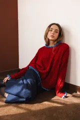 Sweater tejido rojo con cuello alto y puños con volados azules.