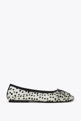 Zapato tipo bailarina de malla color blanco con estampado de lunares negros, detalle de lazo en la puntera, tirador trasero y suela plana.