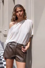 Blusa color crema de corte holgado, con escote asimétrico y manga corta.