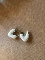 Par de aros dorados con dije en forma de corazón esmaltado en color blanco.