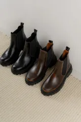 Bota Chelsea de cuero negro con elástico lateral y suela track.