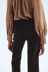 Pantalón de pana de algodón color marrón oscuro, de tiro alto, con piernas acampanadas y bolsillos parche delanteros y traseros.