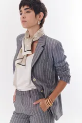 Blazer de lino color crudo con rayas verticales finas en color dorado, de corte recto, con solapas y cierre con un botón.