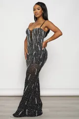 Vestido largo de fiesta negro, corte sirena, con escote en V profundo y breteles finos regulables. Confeccionado en tul elastizado con forro interior y aplique de tul transparente en el escote. Decorado con strass plateados y tornasolados.
