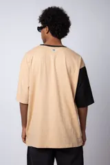 Remera color arena con manga corta negra, cuello redondo con ribete negro y estampado pequeño en el pecho con la frase "Don't worry be happy".