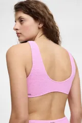Top de bikini color rosa con textura arrugada, escote en V y detalle de nudo en el centro.